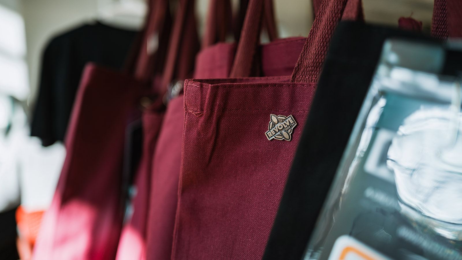 A row of tote bags with metal pins attached to them.